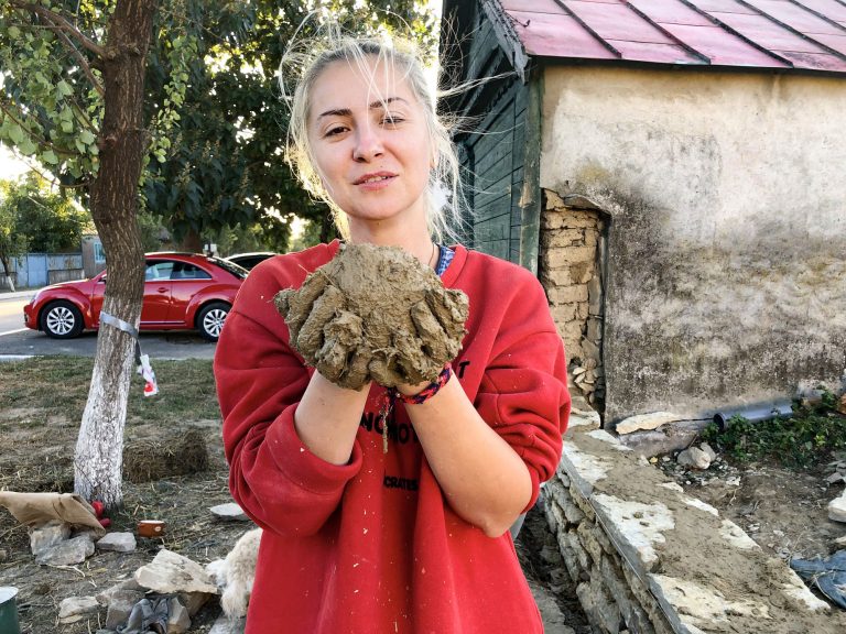 Meșterița de gard ținând în palme amestec de lut și paie pentru gardul din piatră