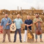 Muzicienii Ansamblului Anton Pann cu oud, kanun, vioară și violoncel, în fața baloților de paie din curtea Lipovenesc