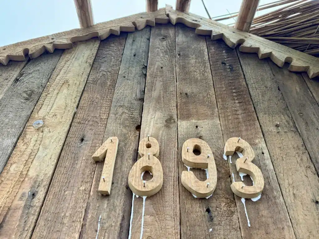 Cifrele 1893 din lemn, prinse pe un fronton din scânduri vechi, cu traforaj sub stuf, la Ferma Lipovenesc din Jurilovca